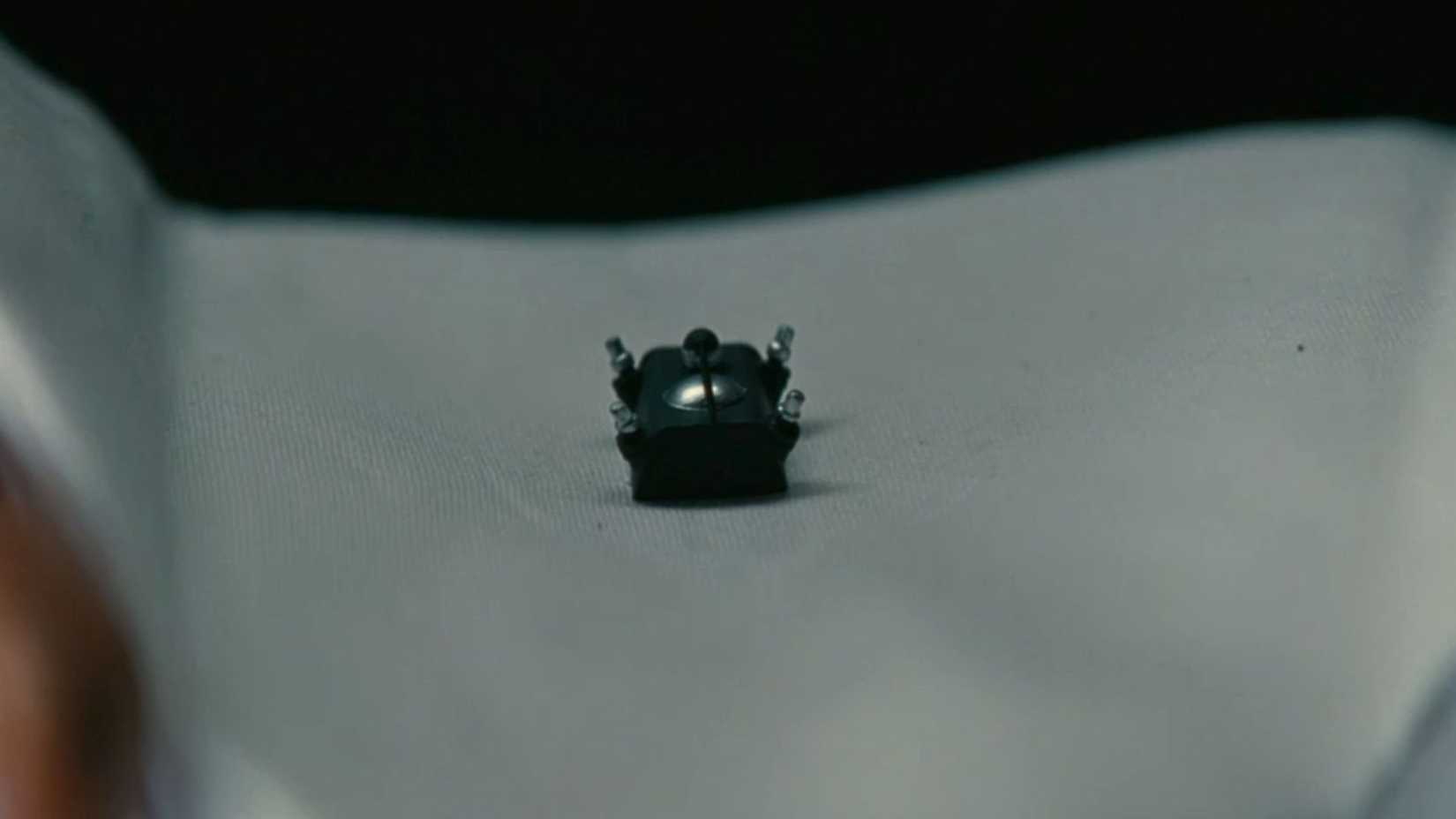 An image from Fallout season 2. It shows a bug-like chip with steel prongs that sits in the middle of a piece of tissue.