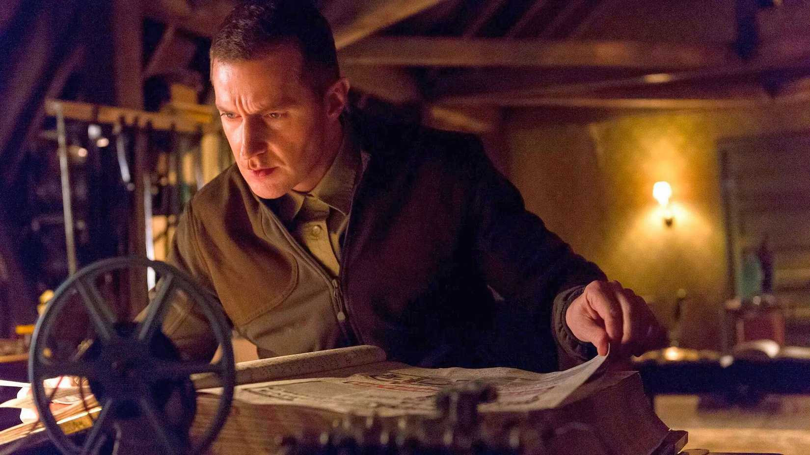 Image from NBC's Hannibal. It features Richard Armitage as Francis Dolarhyde. He has short, cropped hair and is peering over a huge tome. 