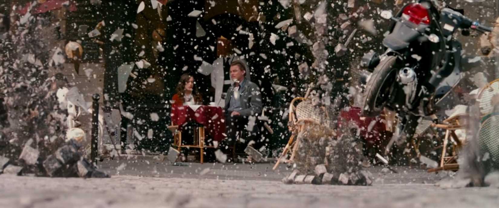 Dom (Leonardo DiCaprio) and Ariadne (Elliot Page) sit in a cafe, obscured by objects bursting apart all around them as a dream environment comes apart in a scene from Christopher Nolan's film Inception