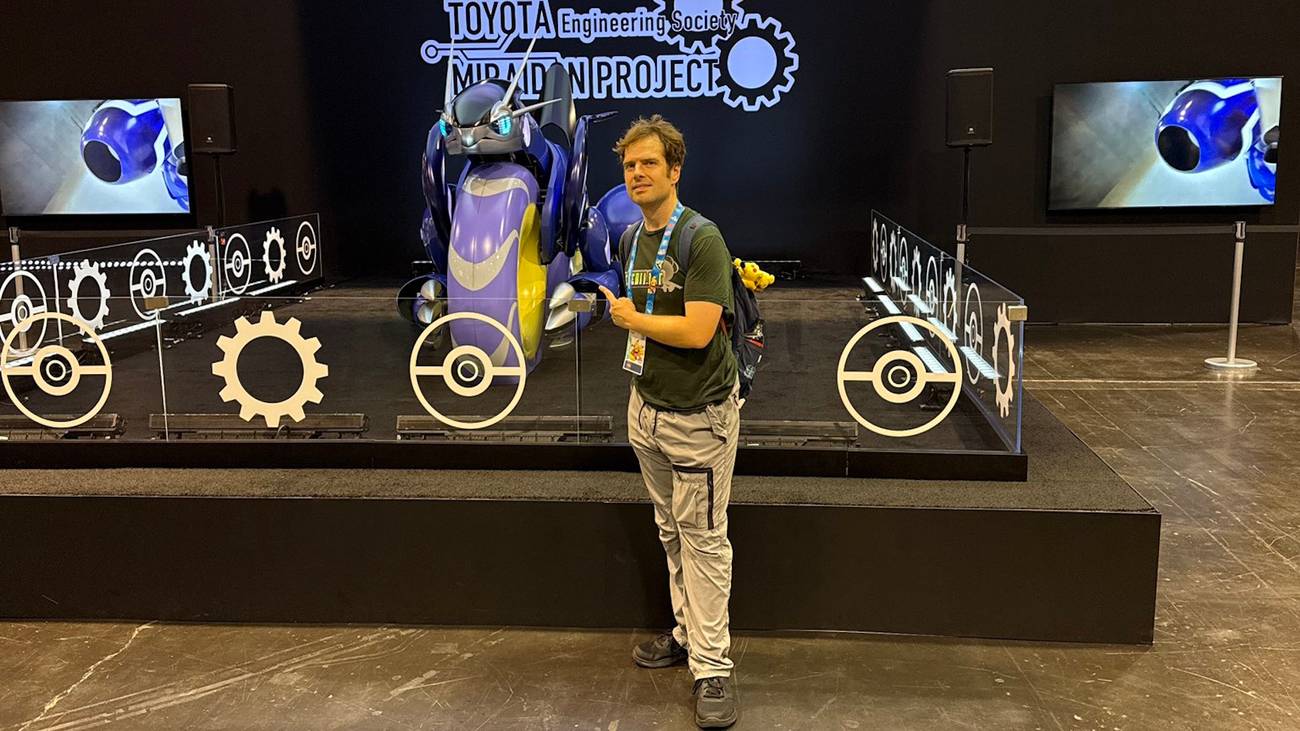 Joe Merrick standing next to a Miraidon model