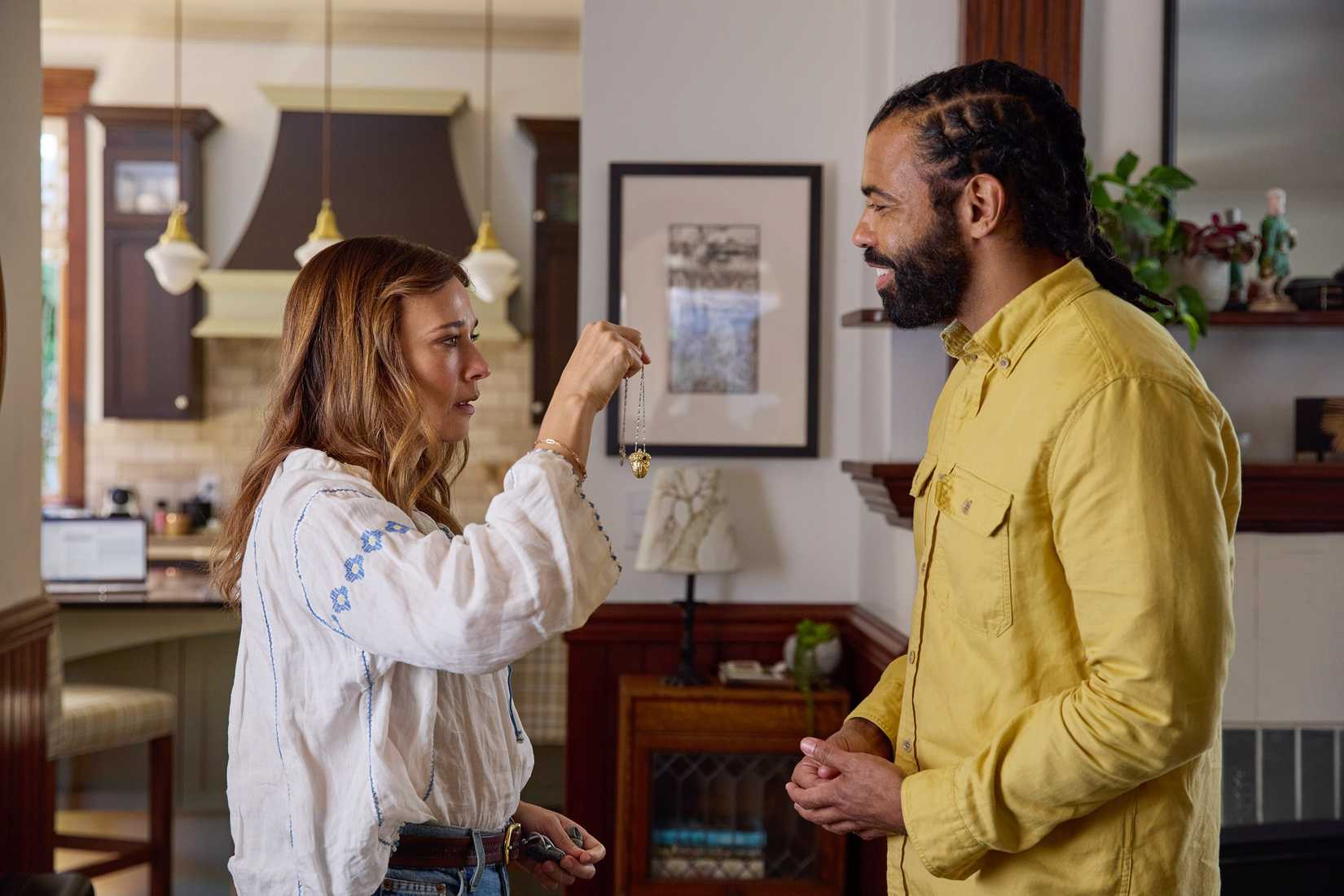 Claire (Rashida Jones) holds up a necklace her boyfriend Greg (Daveed Diggs) has just given her. He watches, smiling. From In the Blink of an Eye