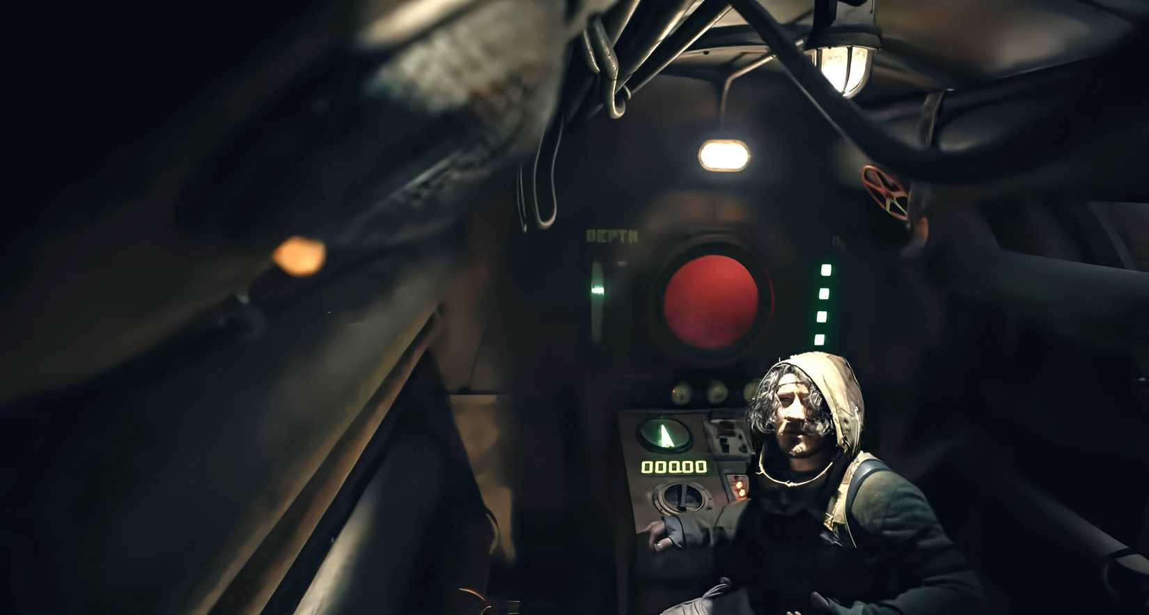 Simon (Mark Fischbach), a dark-haired man lit from above, stands in a dark, dirty, tight futuristic-looking submarine interior in Iron Lung