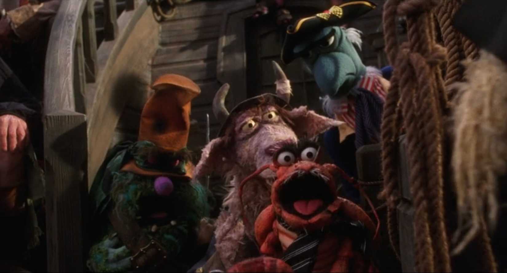 A selection of supporting Muppets from Muppet Treasure Island hanging out on the movie's ship, including Polly, a talking lobster; a fuzzy green pirate; and a talking goat, with Sam the Eagle in the background of the group shot.