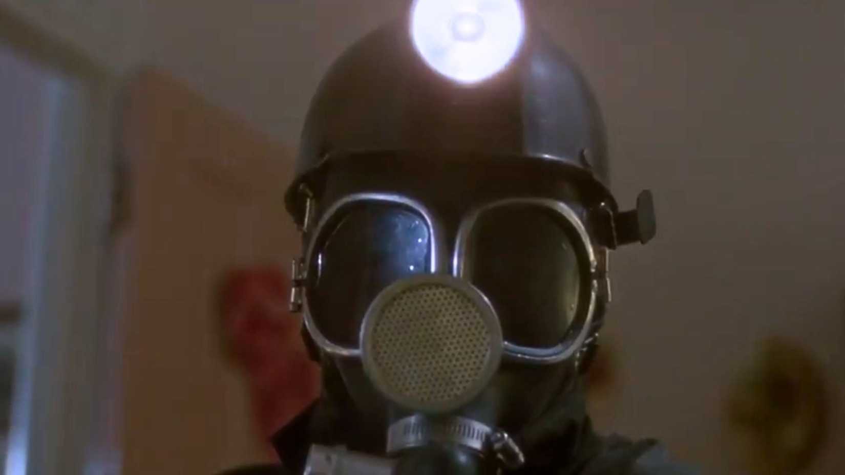 An image of a man decked out in black mining gear. He wears a black, domed helmet with a light on top.
