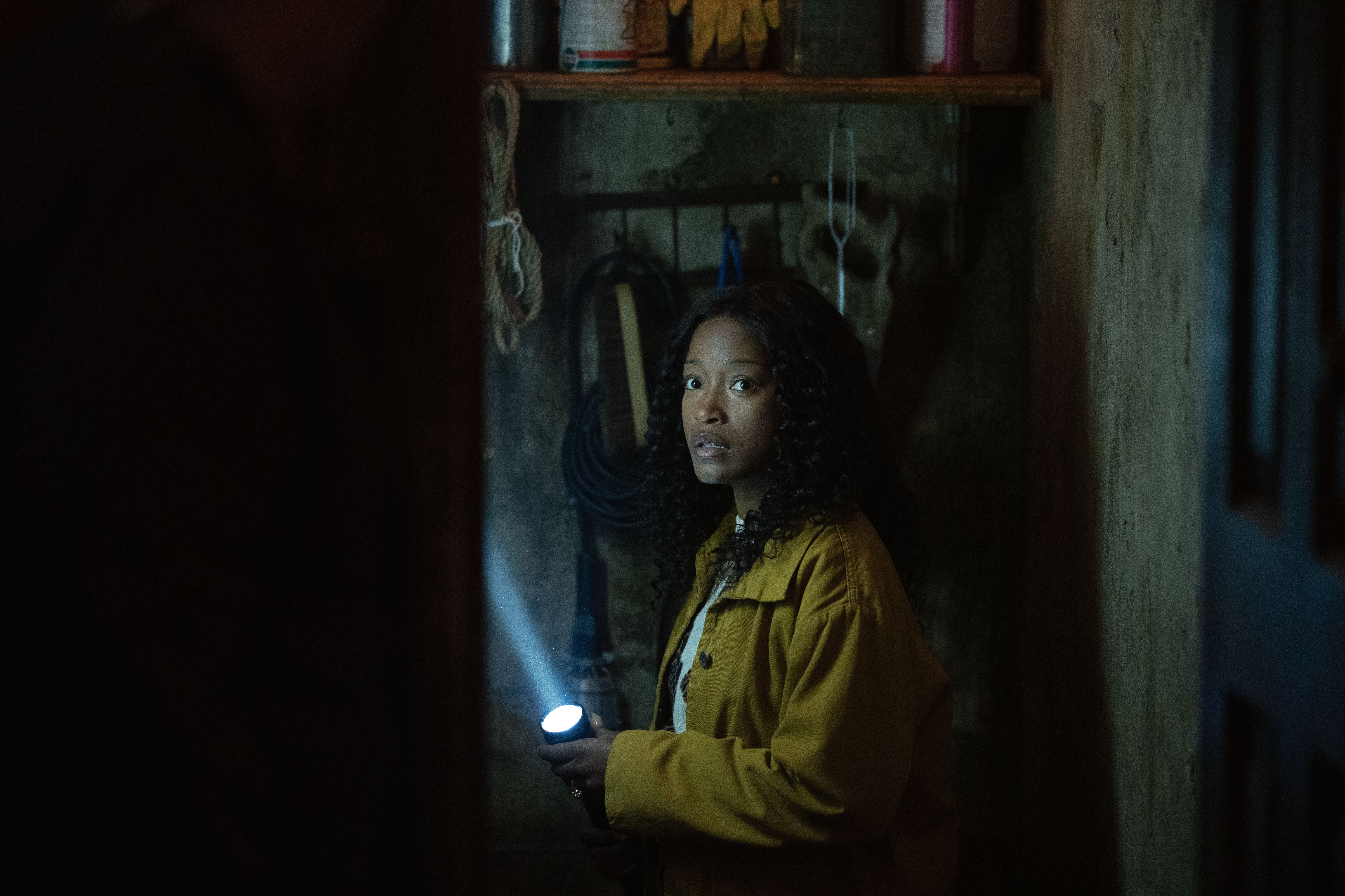 Keke Palmer cautiously exploring with a flashlight in The 'Burbs