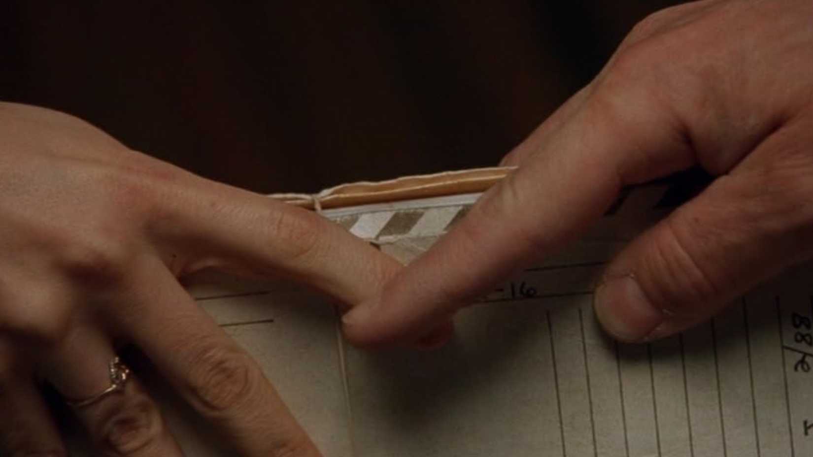 Lecter subtly touches Agent Starling's hand as she passes him some documents.