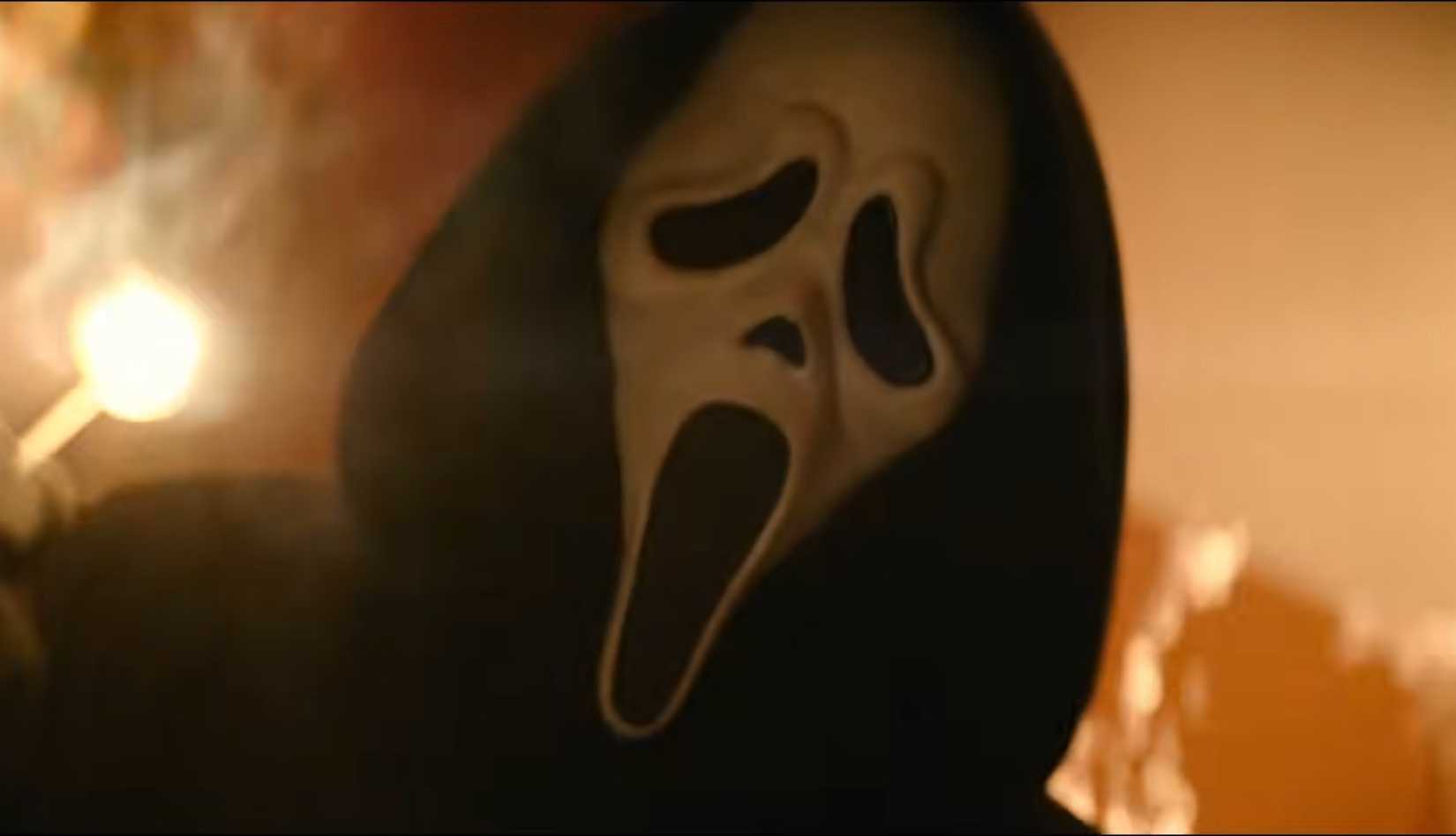 A figure in the iconic Ghostface mask, seen at a slanted angle, holds a lit match poised to burn in a scene from Scream 7.
