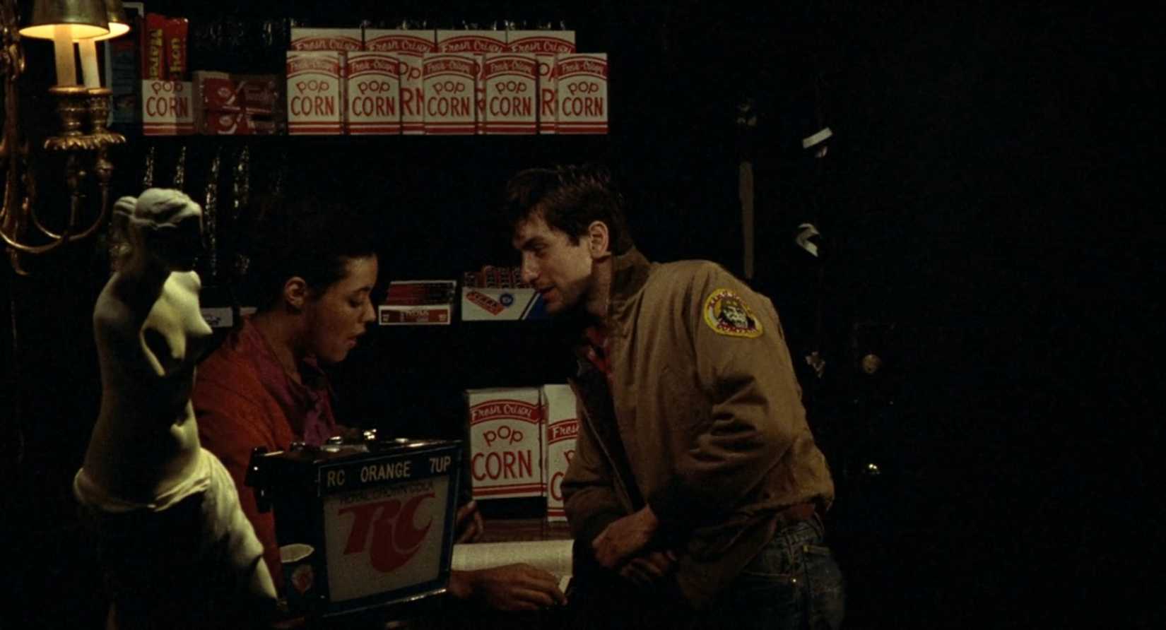In a scene from Taxi Driver, Travis Bickle (Robert De Niro) flirts with an uninterested snack-counter girl at an adult movie theater
