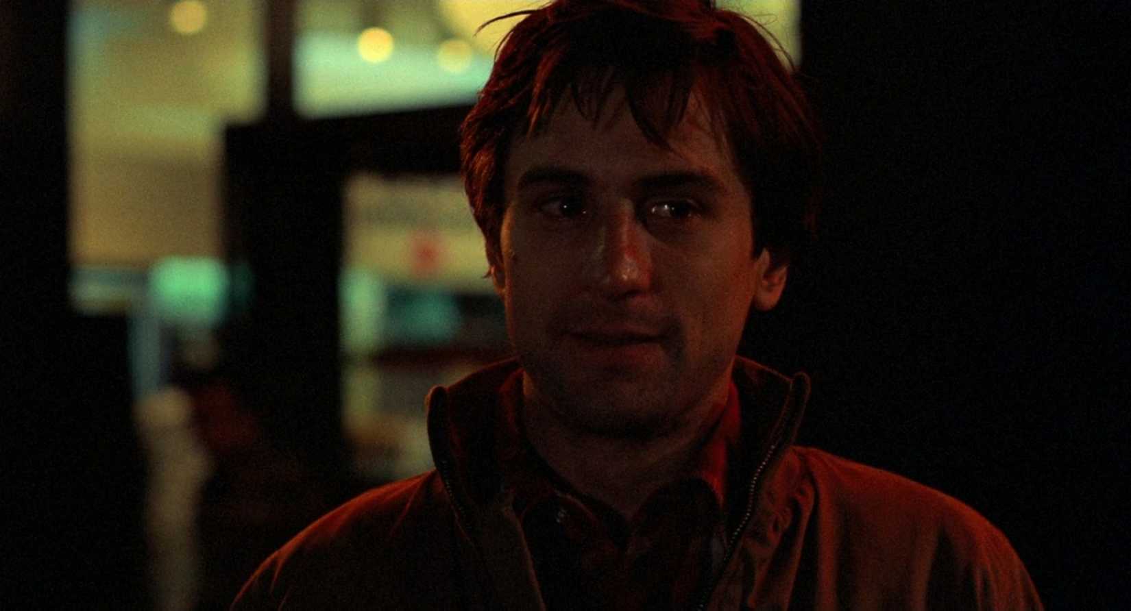 A close-up of Travis Bickle submerged in the crimson glow of Manhattan's neon nightscape.