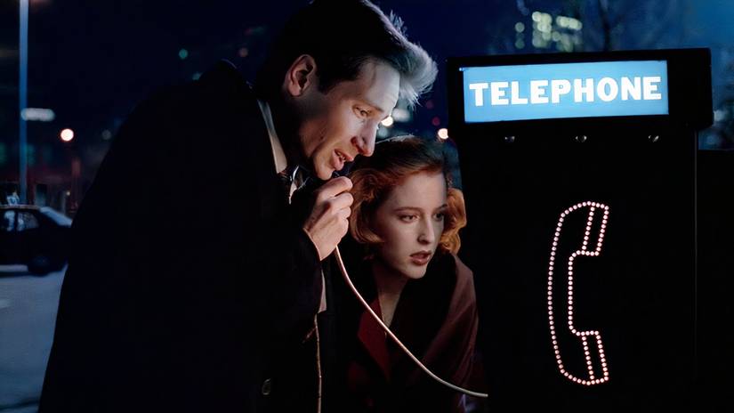 Mulder and Scully conferring in the shadows during the investigation