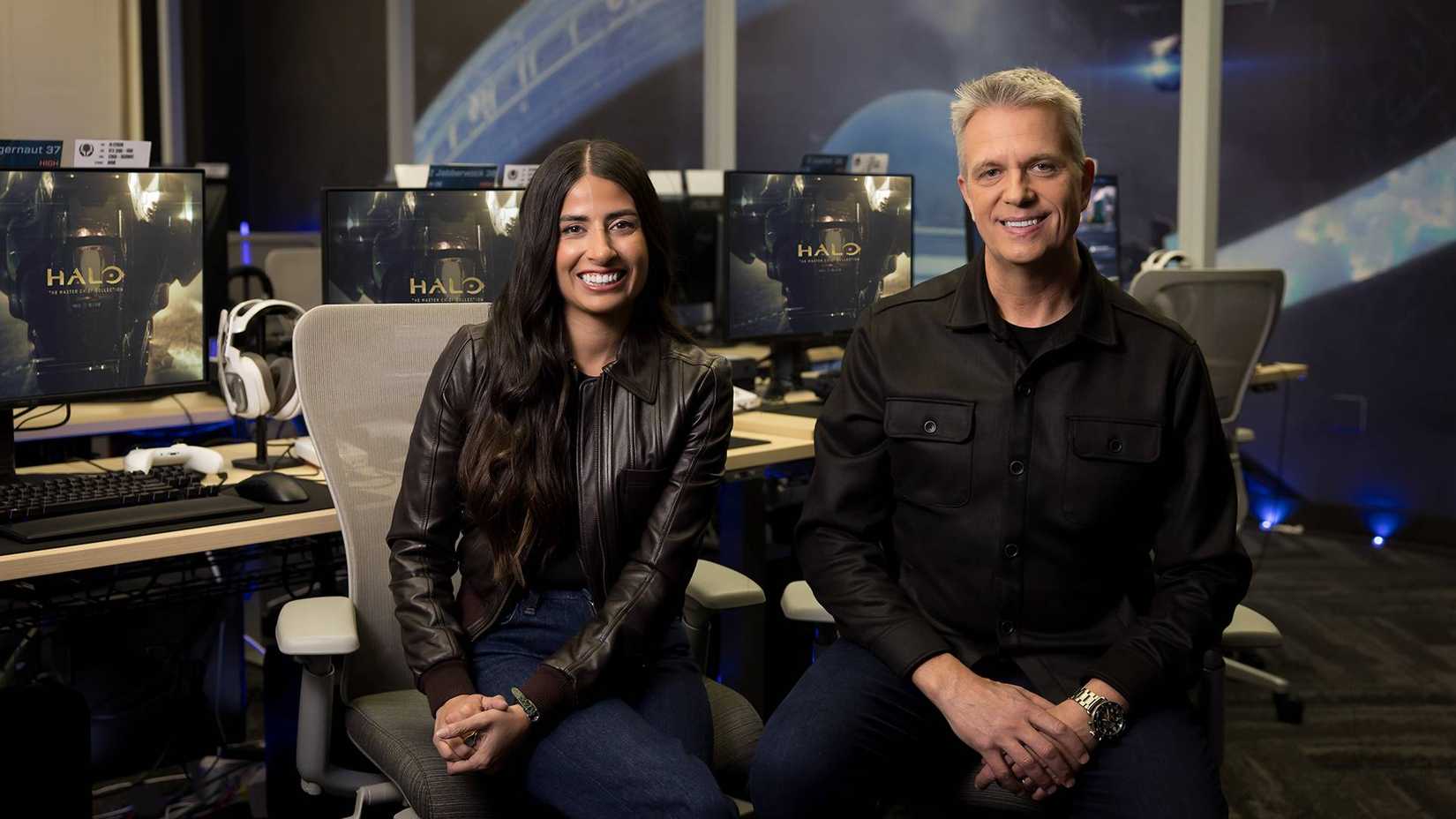 Asha Sharma sat next to Matt Booty in front of monitors showing the Halo Master Chief Collection.