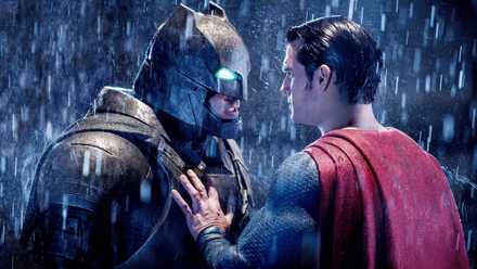 Batman, in a robotic Batsuit, stares down Superman with a glowing glare as rain falls around them in an image from Batman v Superman Dawn of Justice.