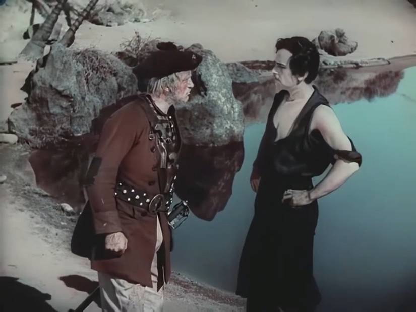 A real pirate looks over a fake pirate (Douglas Fairbanks) by a body of water, in a scene from The Black Pirate that shows off the movie's unusual, muted red-and-green color scheme. 