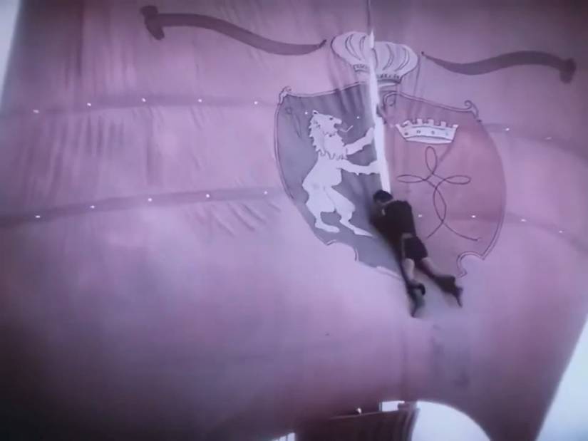 A wide shot of a buccaneer (Douglas Fairbanks) descending a ship's sail by plunging his knife into it and slowing his vertical slide in a scene from The Black Pirate.