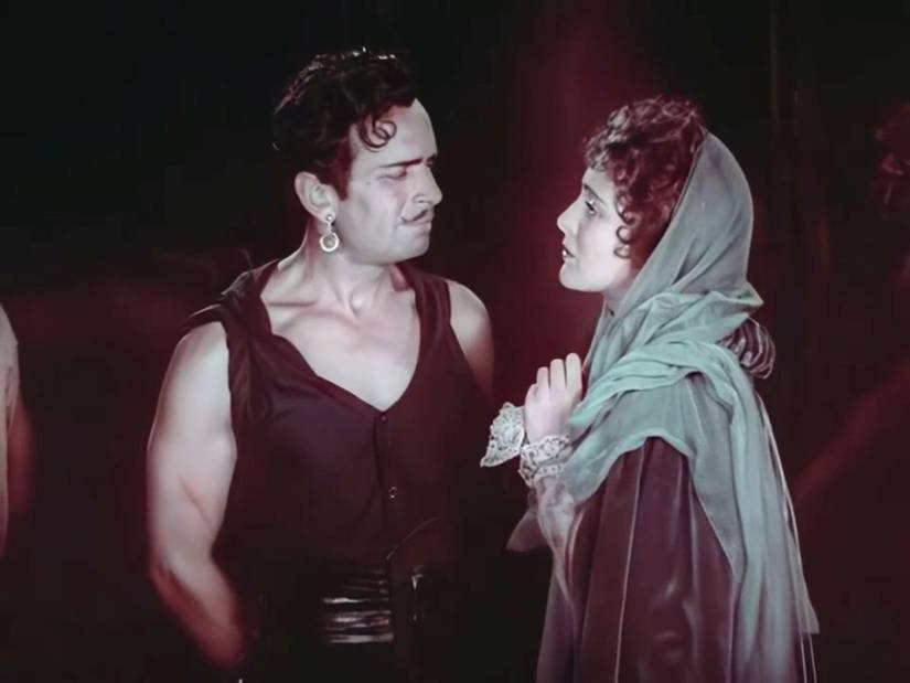 Douglas Fairbanks, playing a swashbuckler disguised as a pirate, is bound with his hands behind his back as he faces the princess (Billie Dove) who loves him