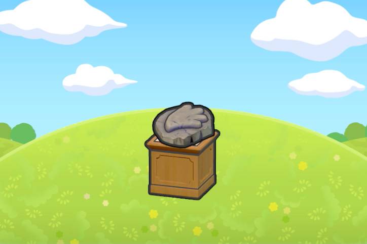 A sail fossil, which looks like a bird's head embedded in a rock, sitting on top of a pedestal on a grassy hill in Pokémon Pokopia.