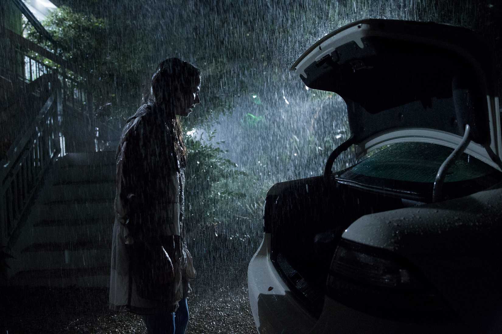Linda Cardellini stands in the dark during a rainstorm, soaking wet, staring into an open car trunk in Bloodline