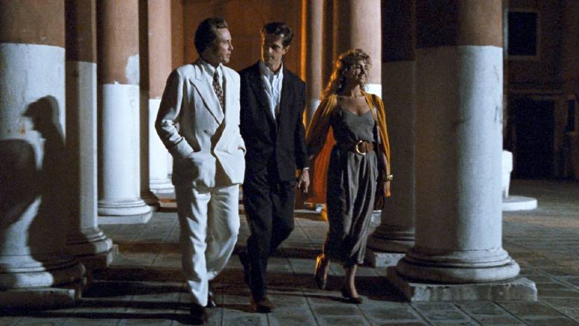 Christopher Walken in white suit leads Rupert Everett and Natasha Richardson through a colonnade at night time in The Comfort of Strangers