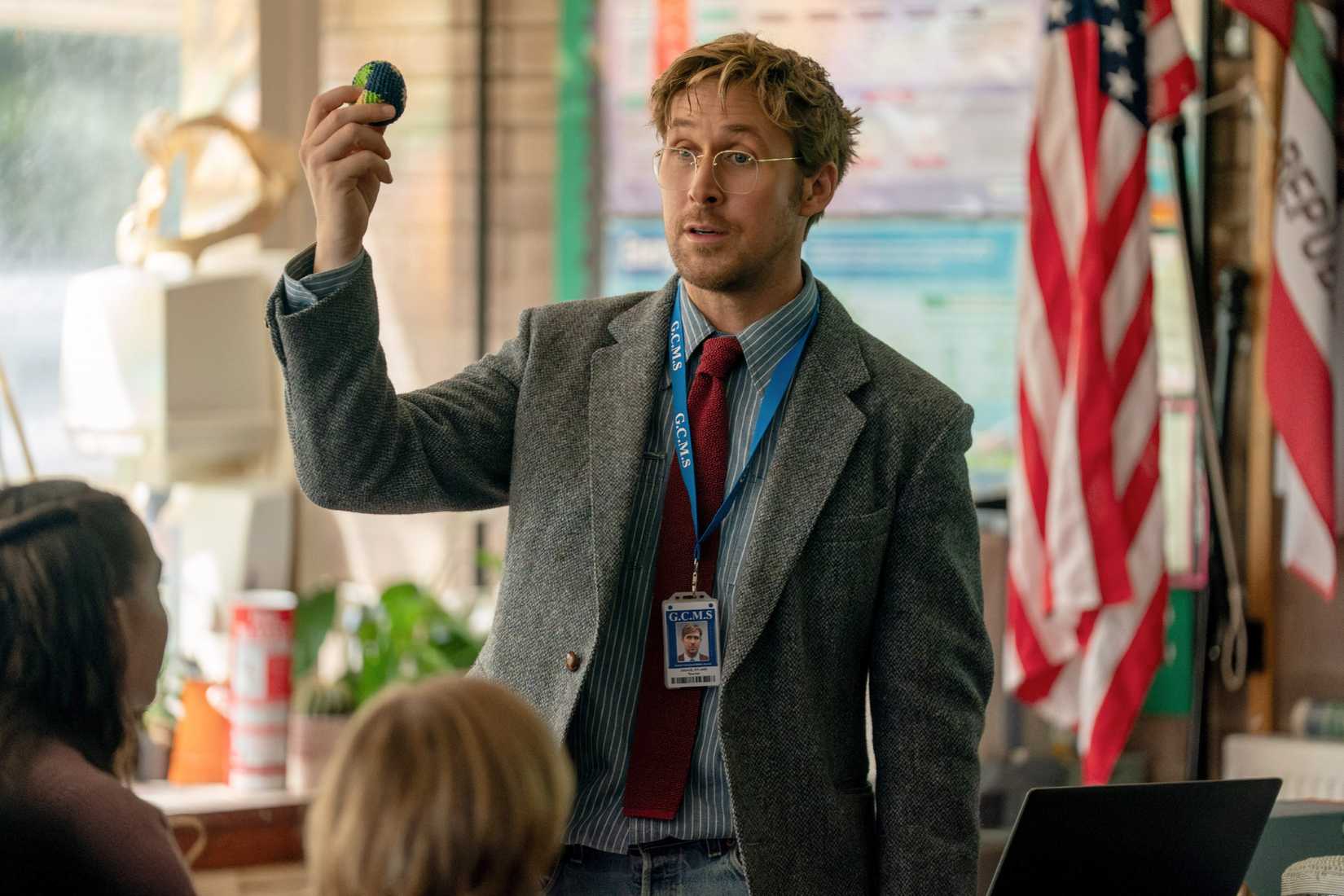 Middle-school science teacher Ryland Grace (Ryan Gosling, disheveled and in a tweedy suit coat) holds up a ball in his classroom in Project Hail Mary