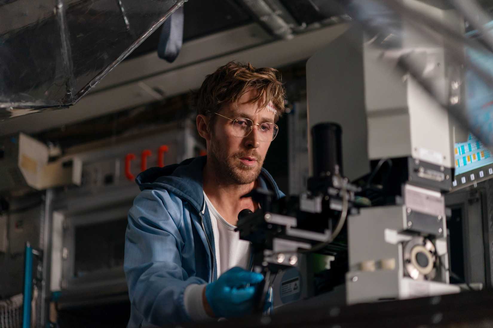 Scientist Ryland Grace (Ryan Gosling) sits in front of a high-tech microscope in Project Hail Mary