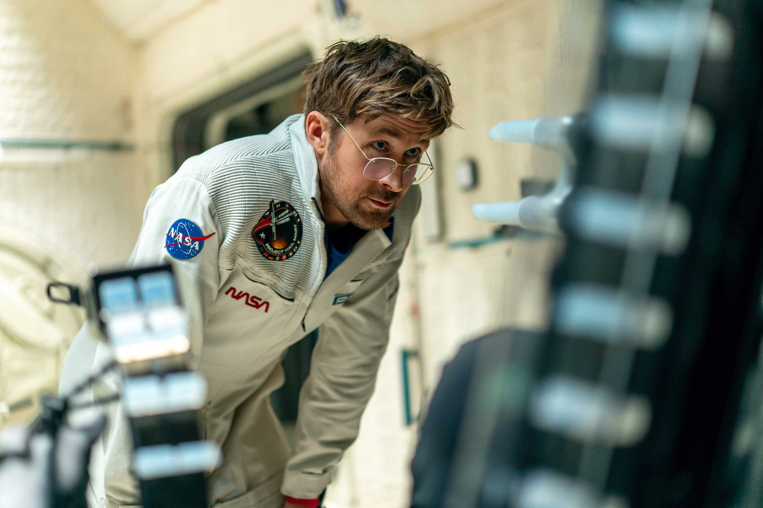 Ryan Gosling in a white NASA jumpsuit staring intently