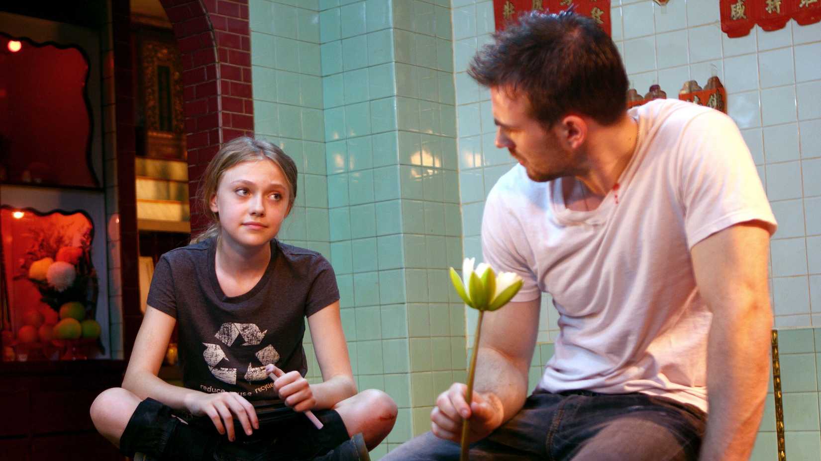 Cassie (Dakota Fanning), a teenage girl, sits next to Nick (Chris Evans) who is holding a lotus flower in Push