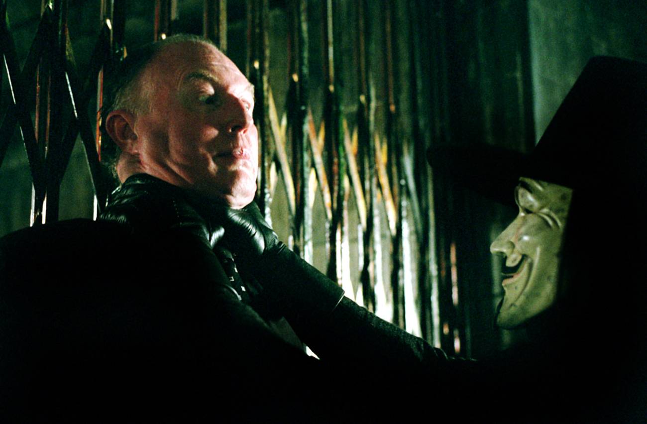 Crowds in Guy Fawkes masks facing off against military forces.