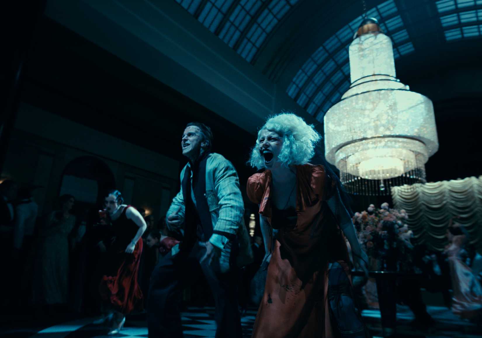 Frankenstein (Christian Bale) and Ida (Jessie Buckley) scream as they lead a squad of dancers through a hunching, lurching dance in The Bride!