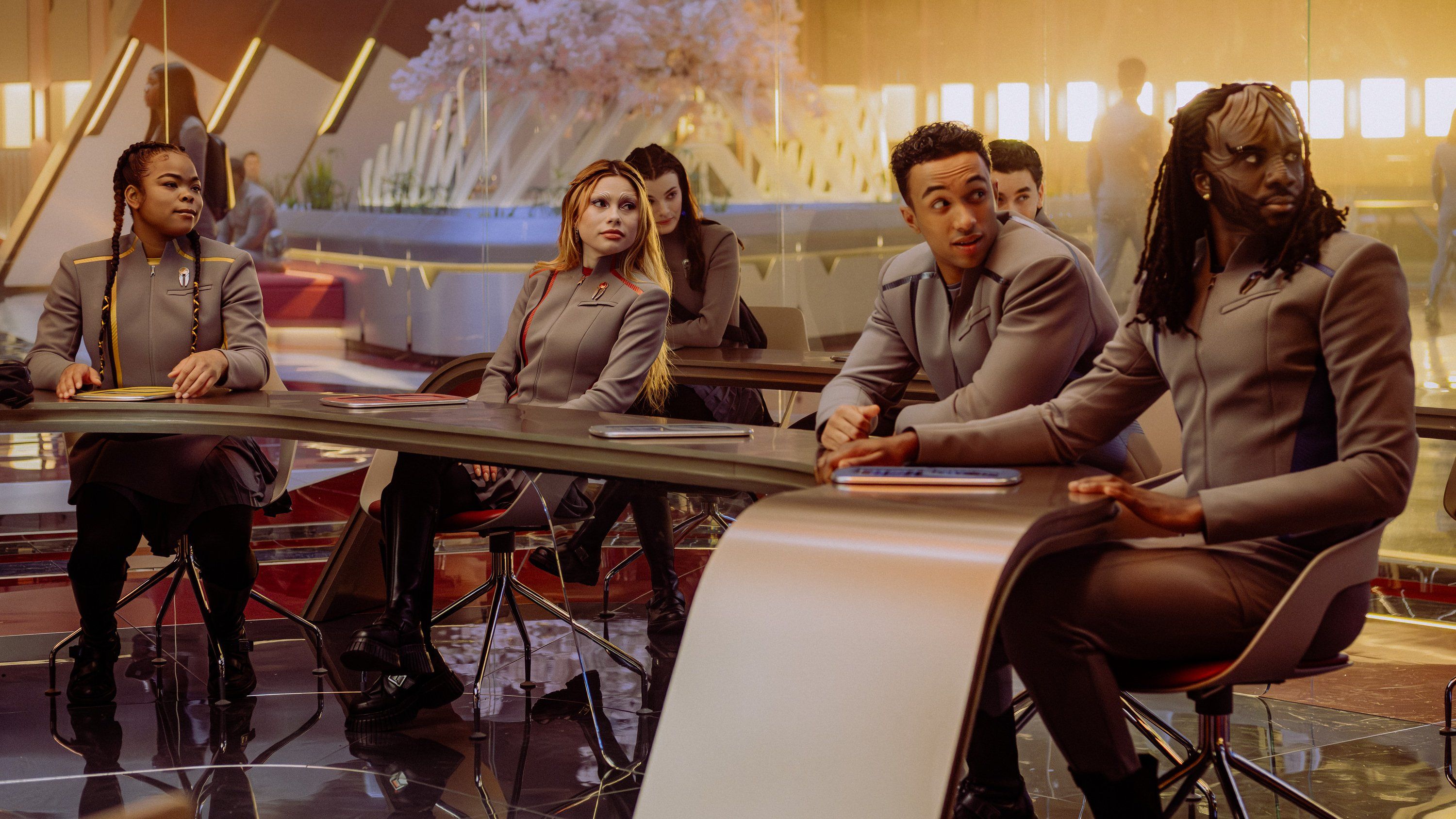 SAM (Kerrice Brooks), Genesis Lythe (Bella Shepard), Caleb Mir (Sandro Rosta), Jay-Den Kraag (Karim Diané), Tarima Sadal (Zoë Steiner) and Darem Reymi (George Hawkins) sit at desks in a classroom in Starfleet Academy