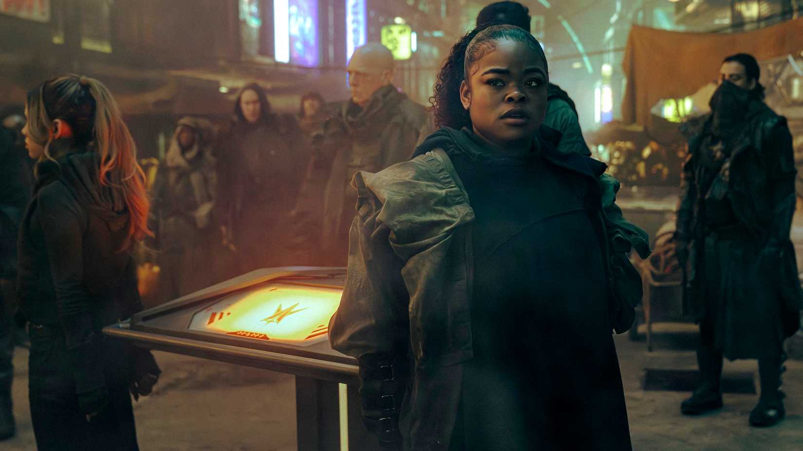 SAM (Kerrice Brooks) looks concerned while standing in a crowded marketplace in Starfleet Academy