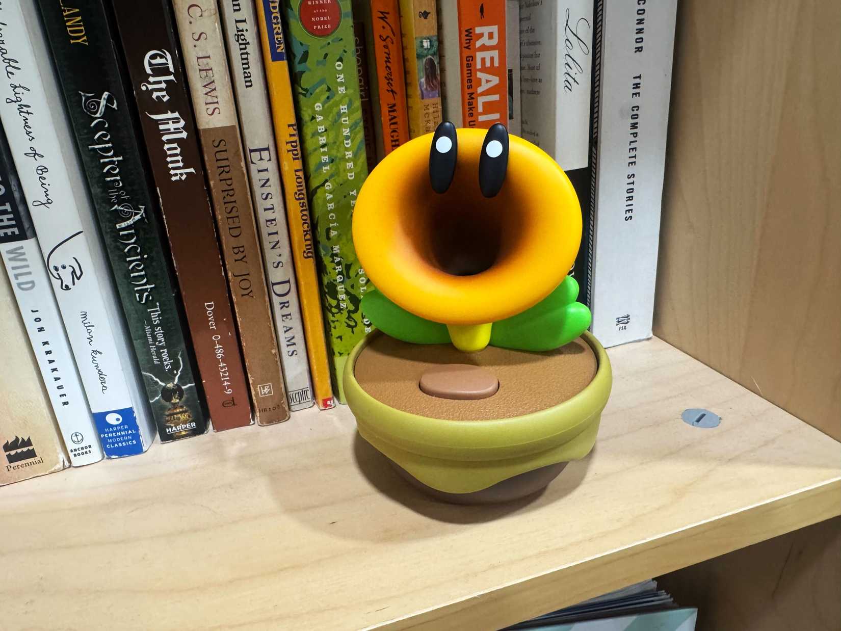 A Talking Flower toy sits on a bookcase.