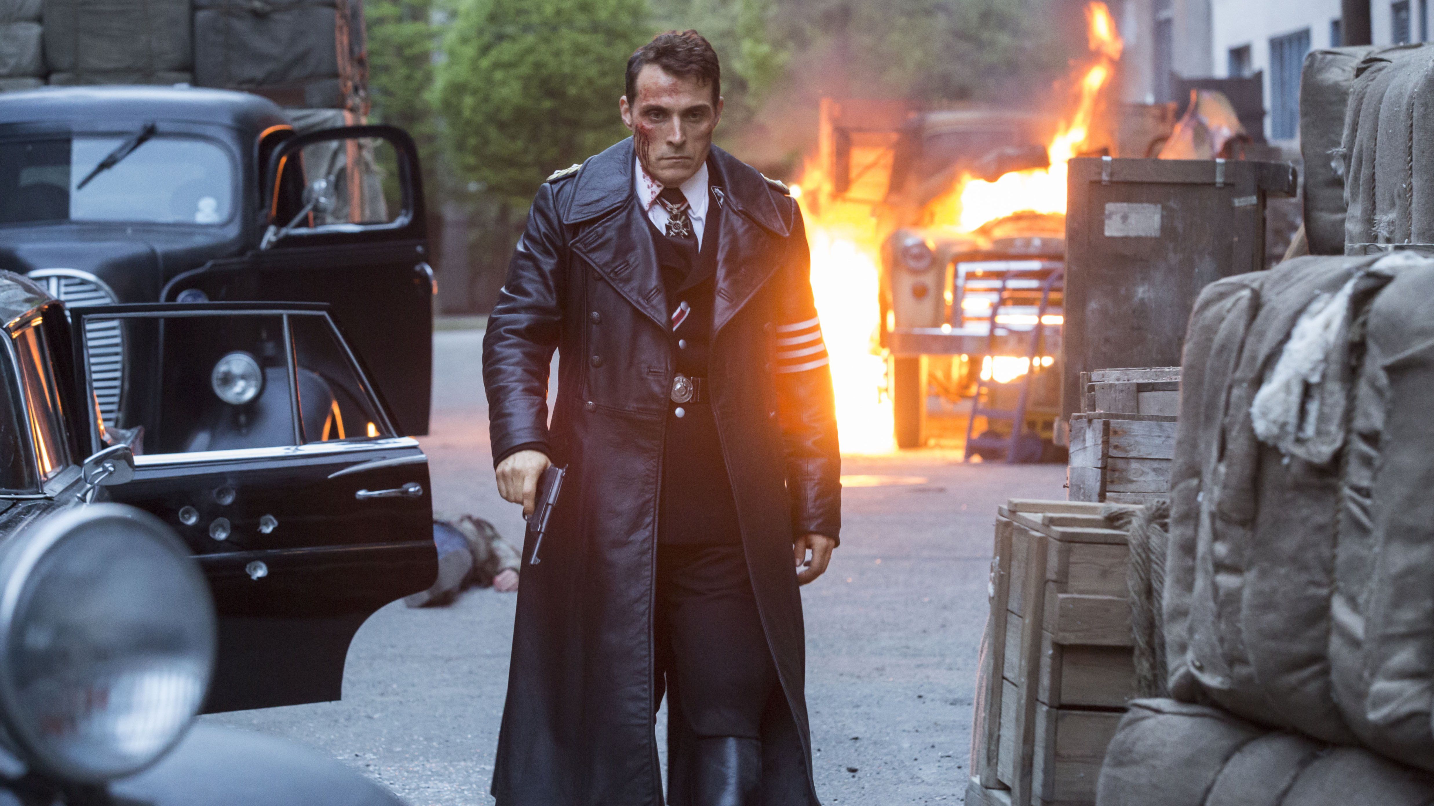 John Smith (Rufus Sewell) walks away from a fire on the streets with blood streaming down his face in The Man in the HIgh Castle.