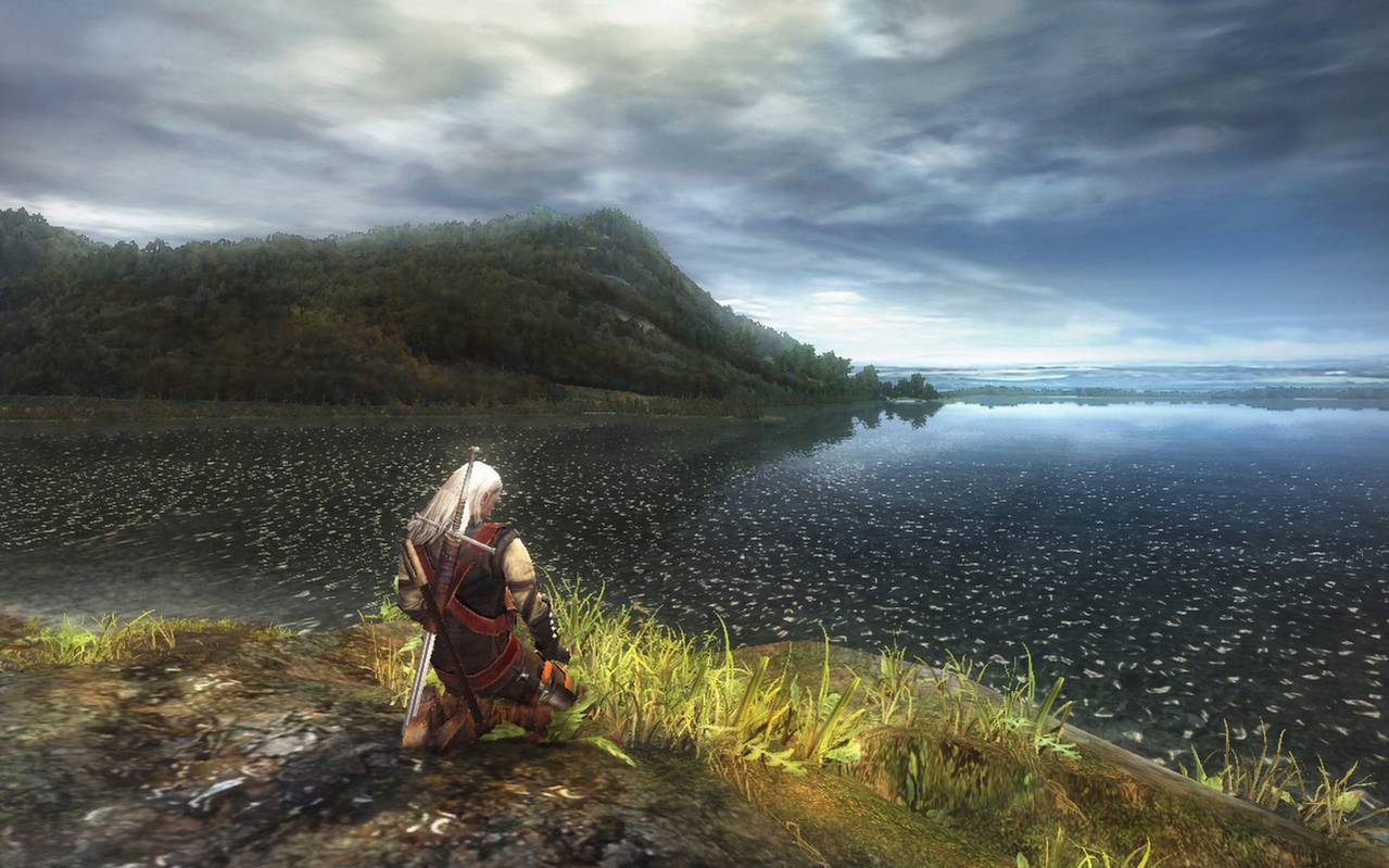 Geralt kneels before a lake in the first Witcher game