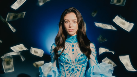 AI actress Tilly Norwood walks amidst falling money in a screenshot from its music video for Take the Lead