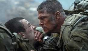 Army sergeant 81 (Alan Ritchson) leans over a fellow solder and covers their mouth with his hand to keep them quiet in War Machine