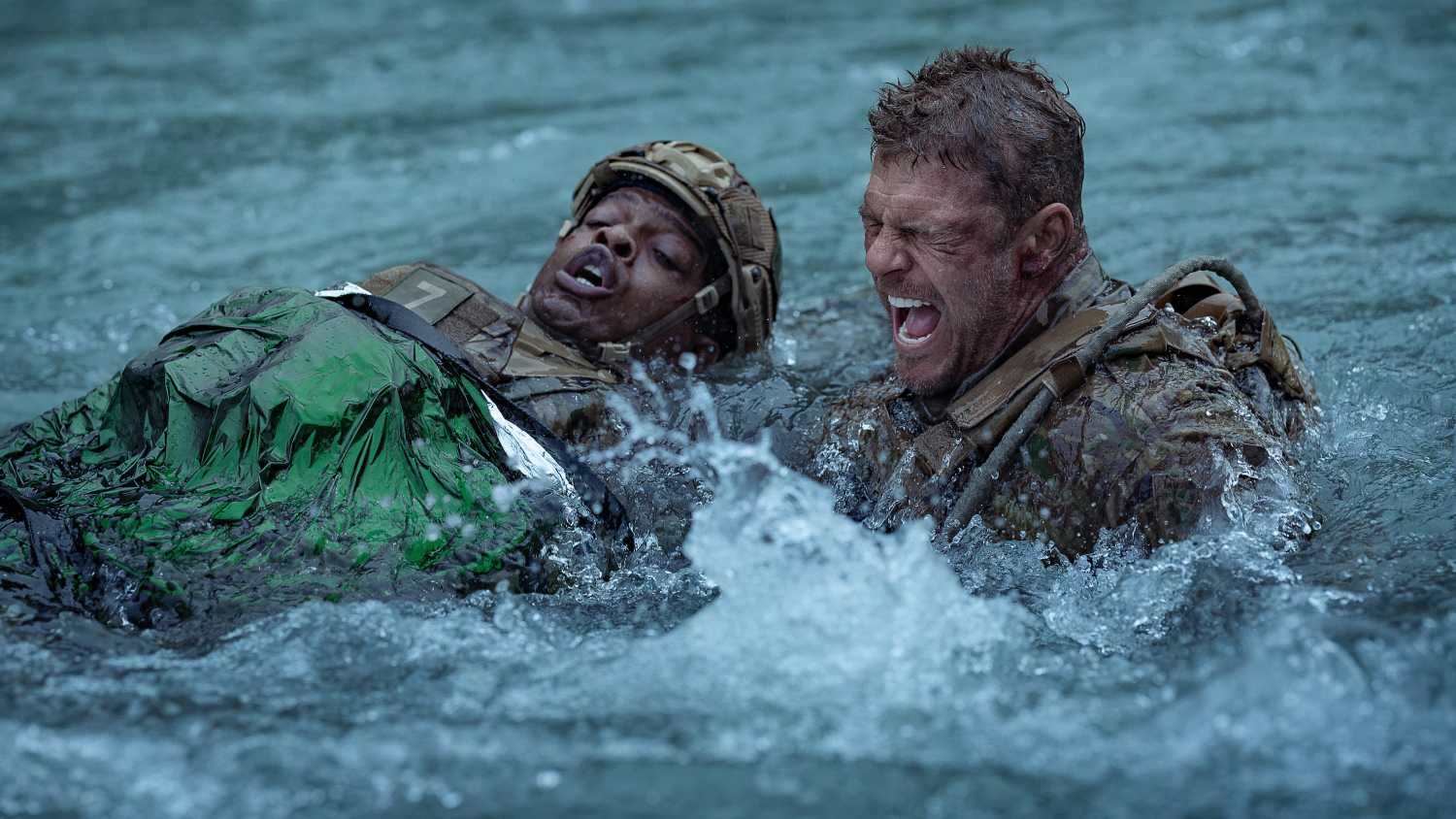 Army sergeant 81 (Alan Ritchson) screams as he swims across a raging river, dragging a wounded fellow soldier, in War Machine