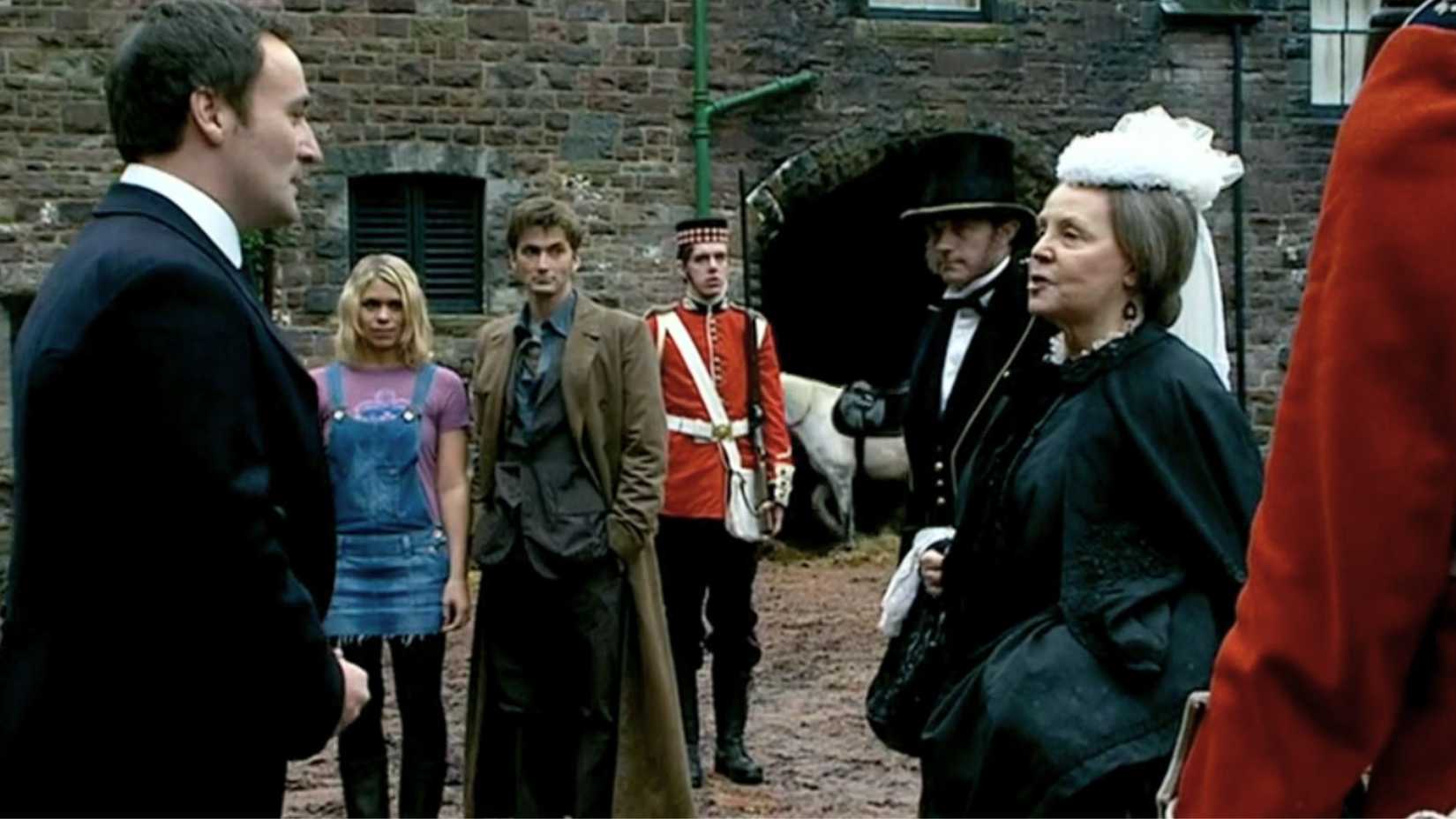 An image featuring Doctor Who's Billie Piper and David Tennant as Rose Tyler and the Doctor. Queen Victoria, dressed in black, speaks to a man in a suit.