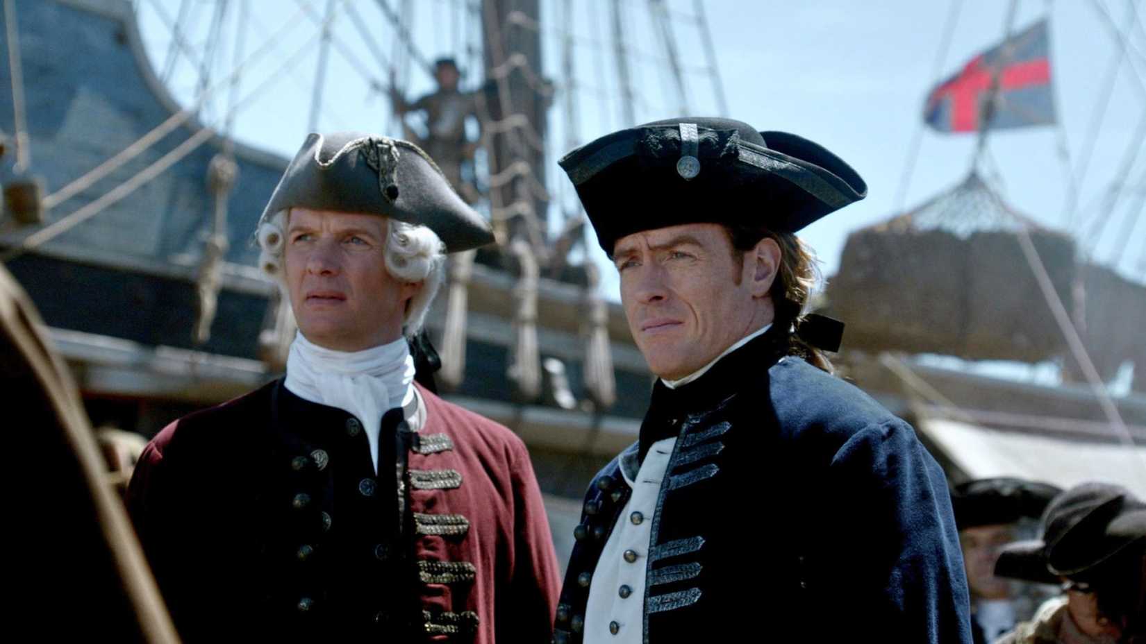 Thomas Hamilton, sporting a tricorn hat and a red coat, stands next to Captan Flint who also wears the same outfit, but his coat is blue to signify his rank as a Royal Navy officer.