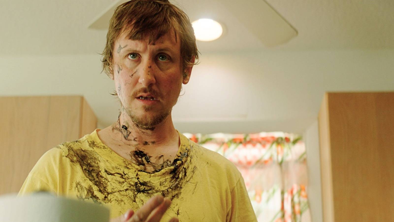 Johnny Pemberton as Doug. He wears a yellow shirt that is covered in dark ink. 