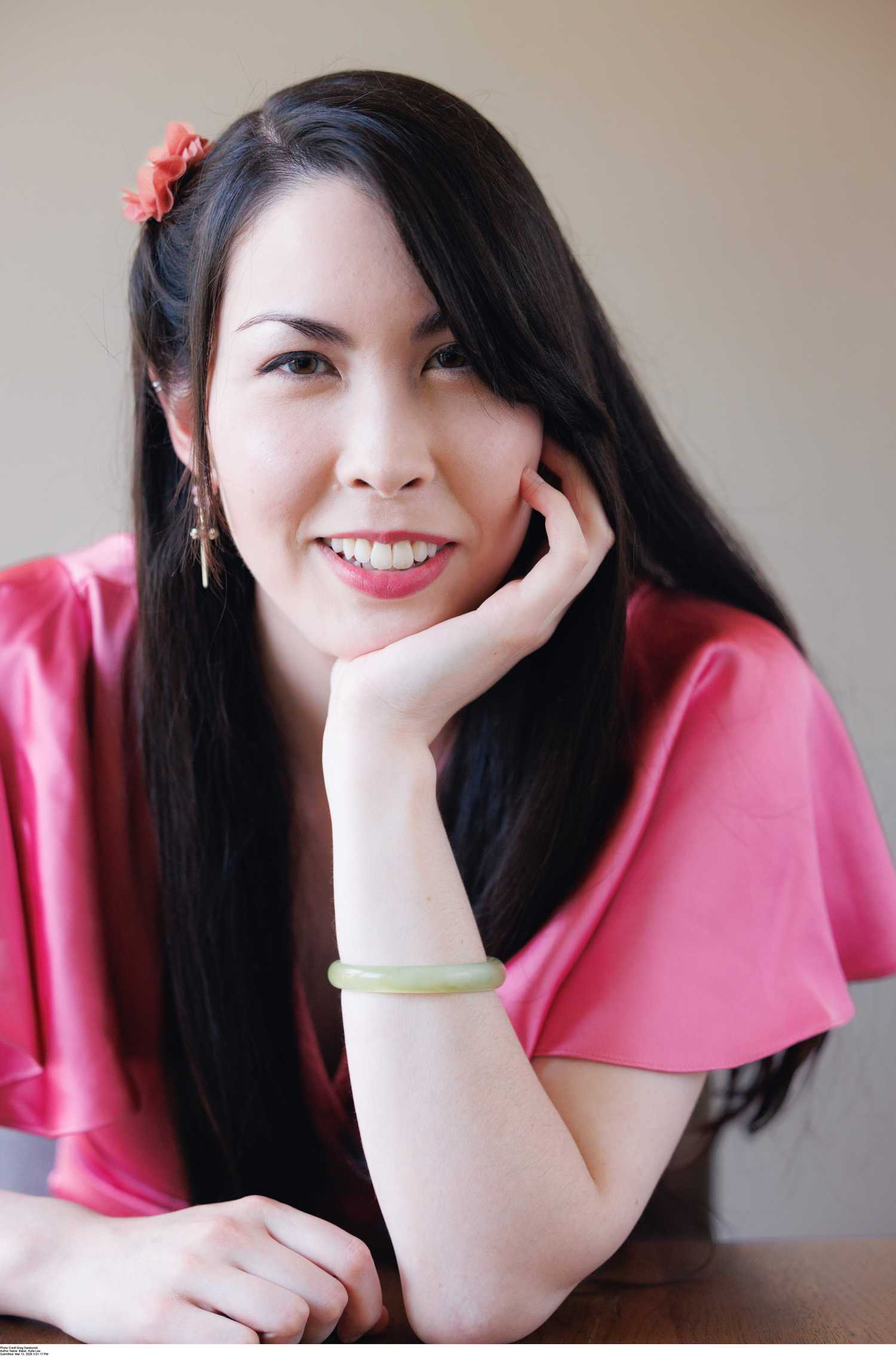 A portrait of Kylie Lee Baker, a woman of Asian descent with long black hair, wearing a pink blouse