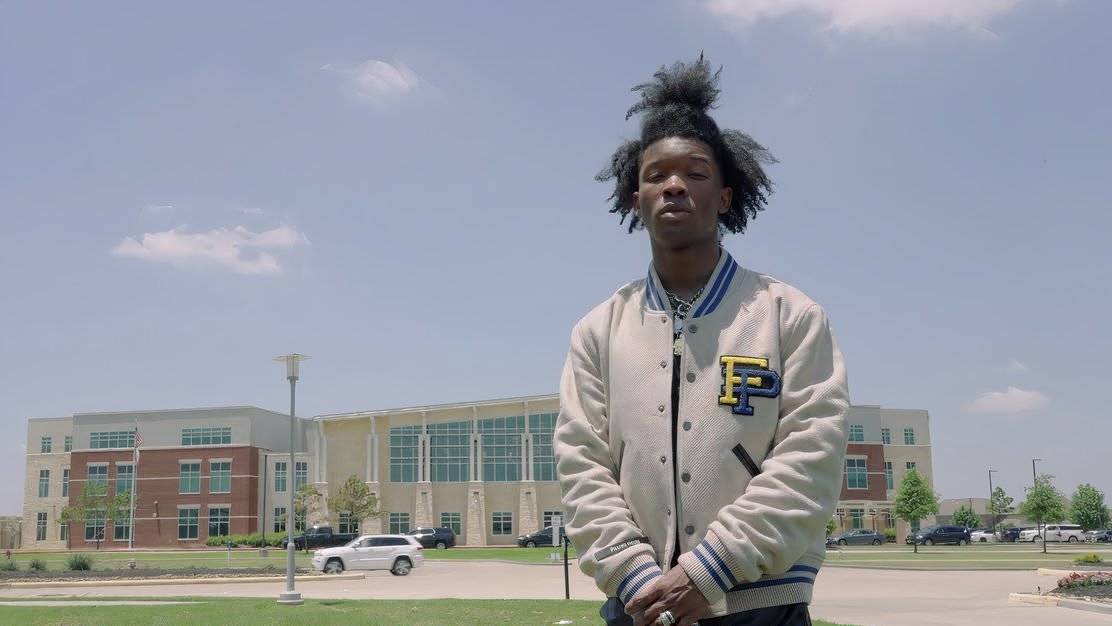 d4vd stands before a large school building in a photo