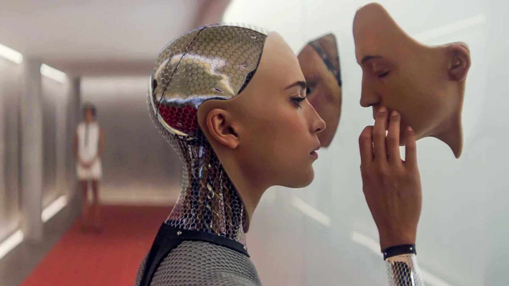 Still from Ex Machina featuring Ava touching a plastic face on the wall. 
