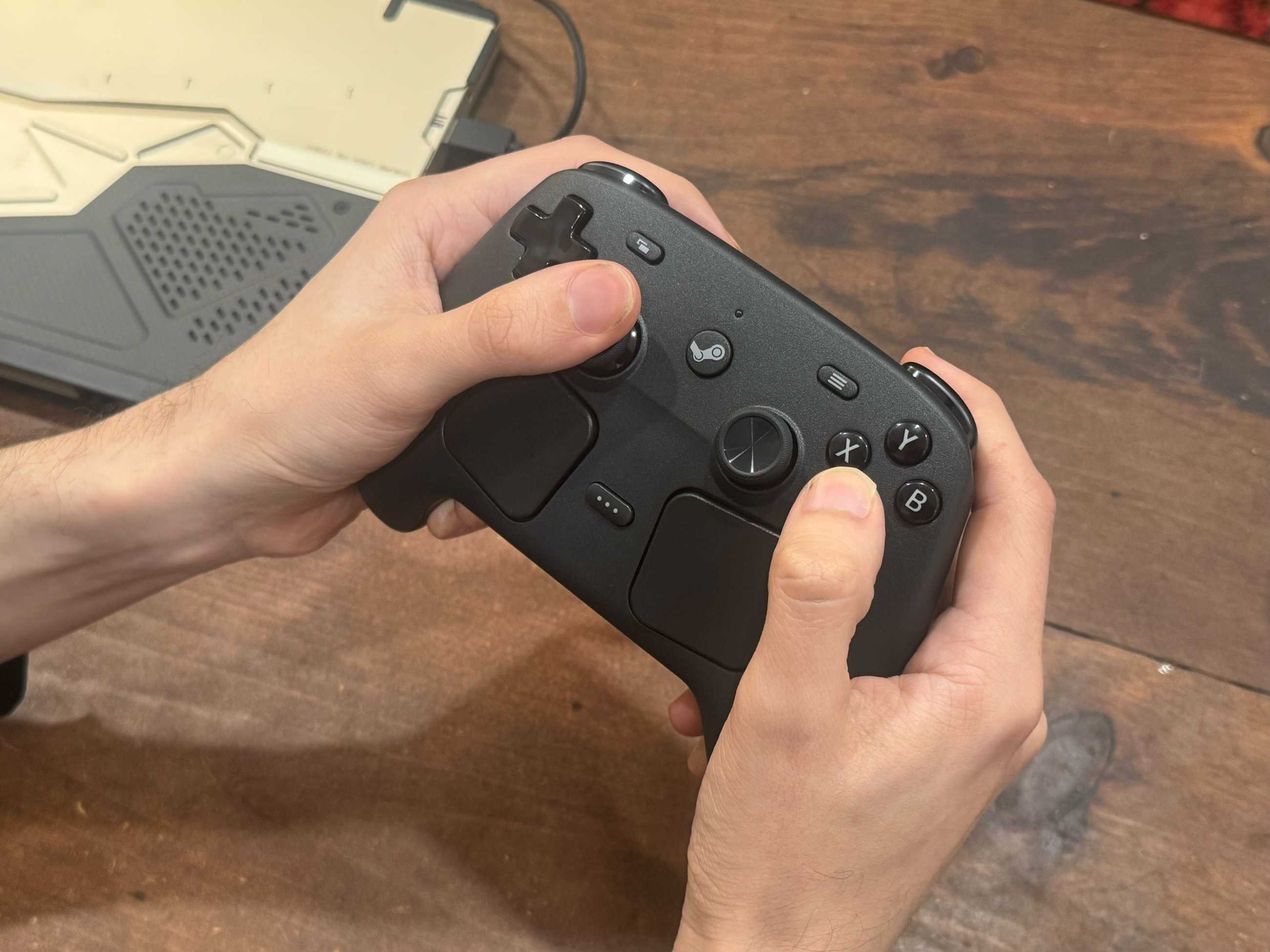 Hands hold a Steam Controller.