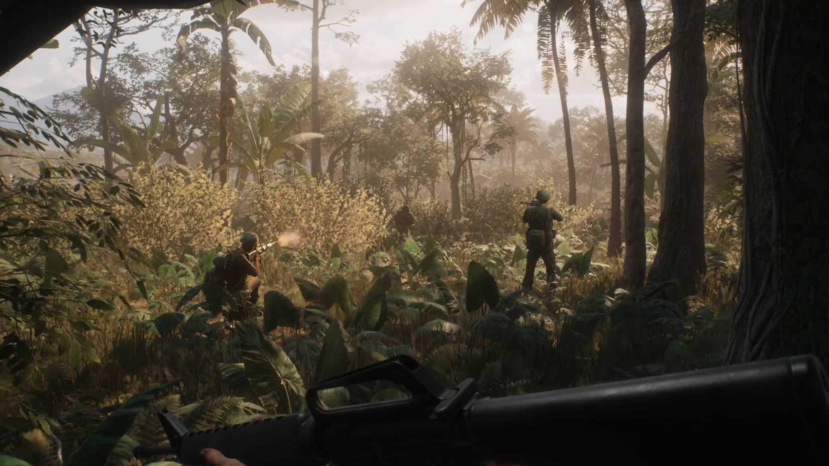 A soldier in Hell Let Loose: Vietnam standing with an assault rifle in the jungle behind three of their teammates.