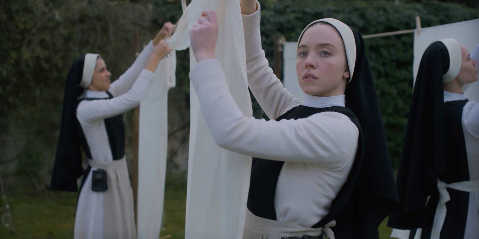 A young nun (Cecilia) hangs washed clothes while looking concerned in Immaculate