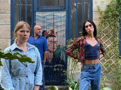 Three people standing in front of a Frida Kahlo bead curtain