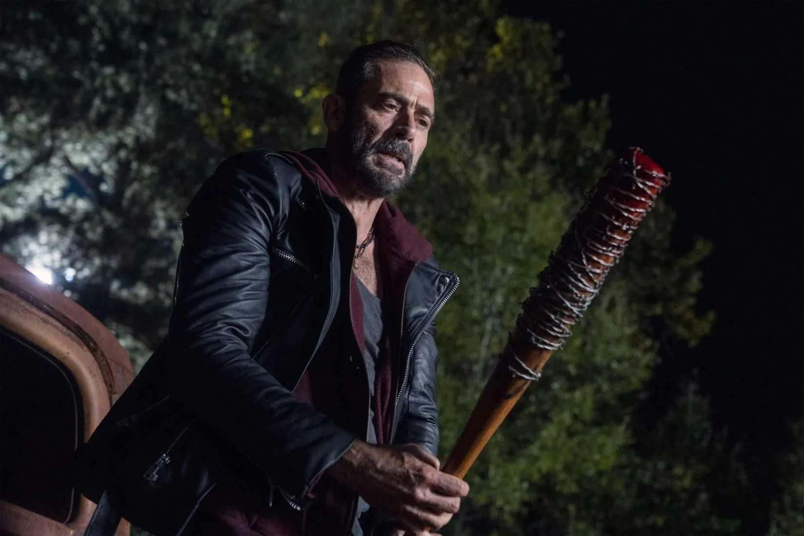 Negan (Jeffrey Dean Morgan), a dark-haired man in a leather jacket, raises his blood-stained, barbed-wire-wrapped bat "Lucille" in The Walking Dead
