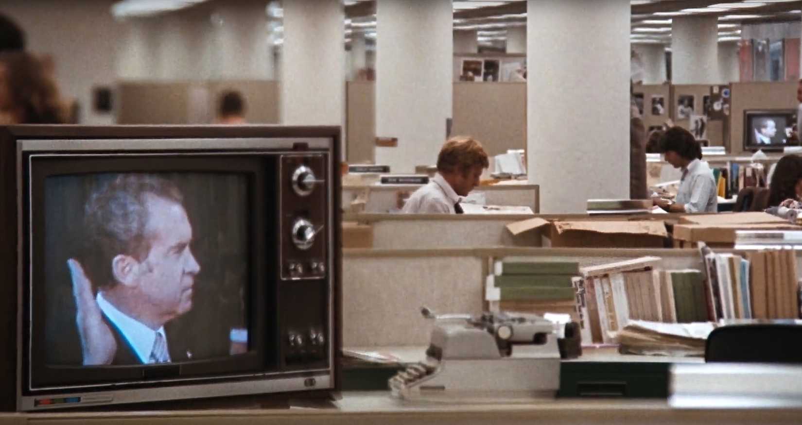 On TV, Nixon takes the Oath of Office as Woodward and Bernstein are typing in the background