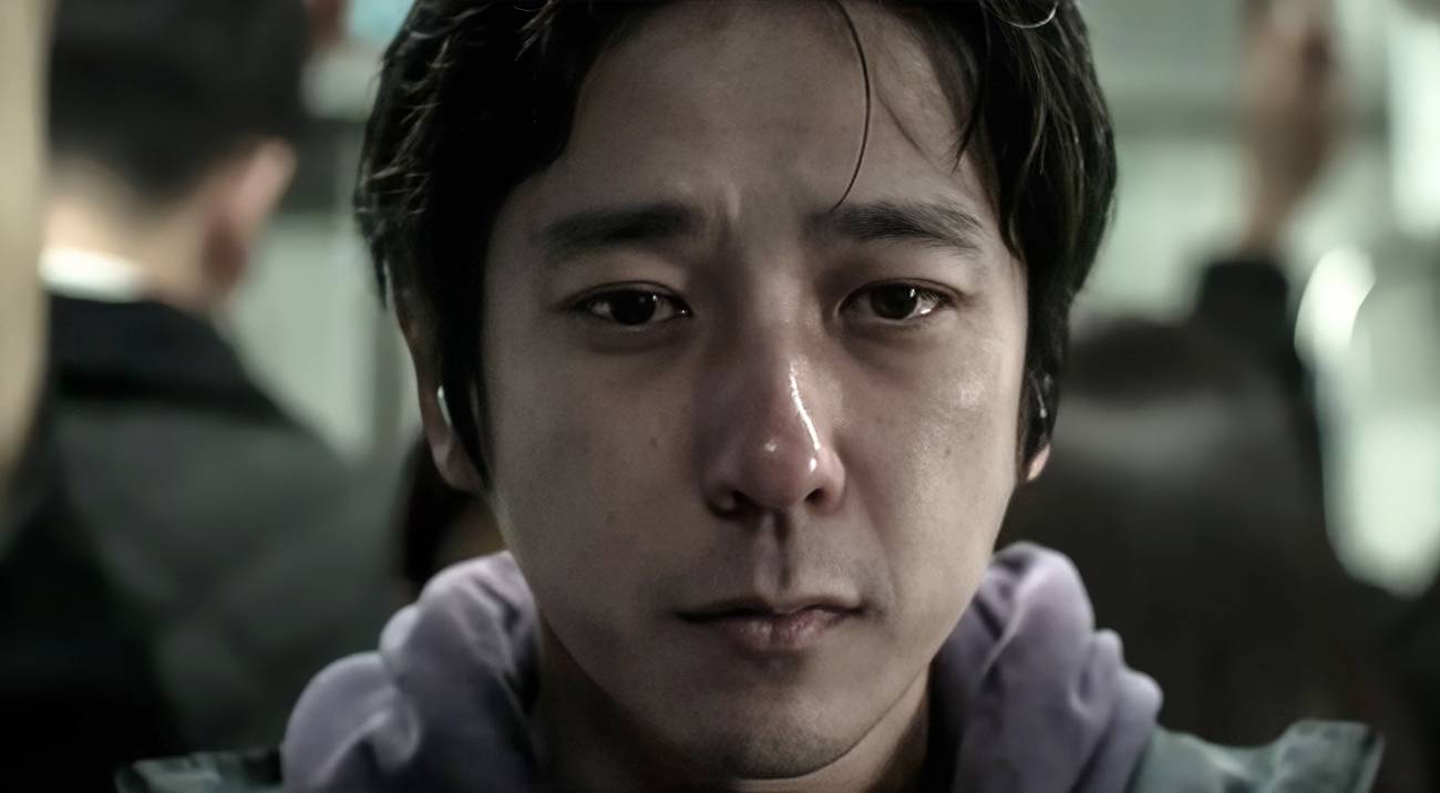 The Lost Man (Kazunari Ninomiya), a young Japanese man in a hoodie, seen in close-up with a red nose and watery eyes as if he's been crying, in Exit 8