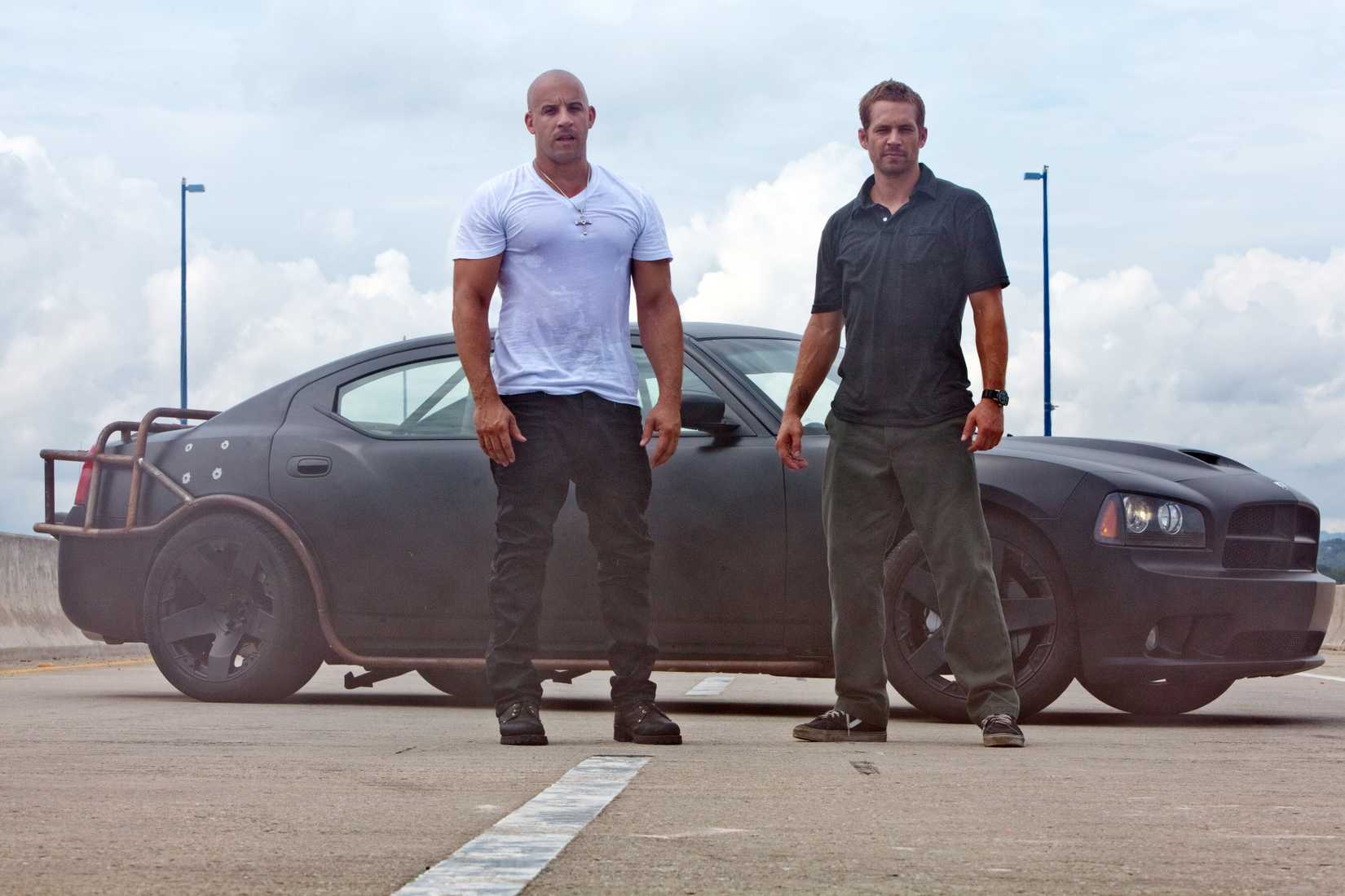 Dominic and Brian stand beside a Dodge Charger